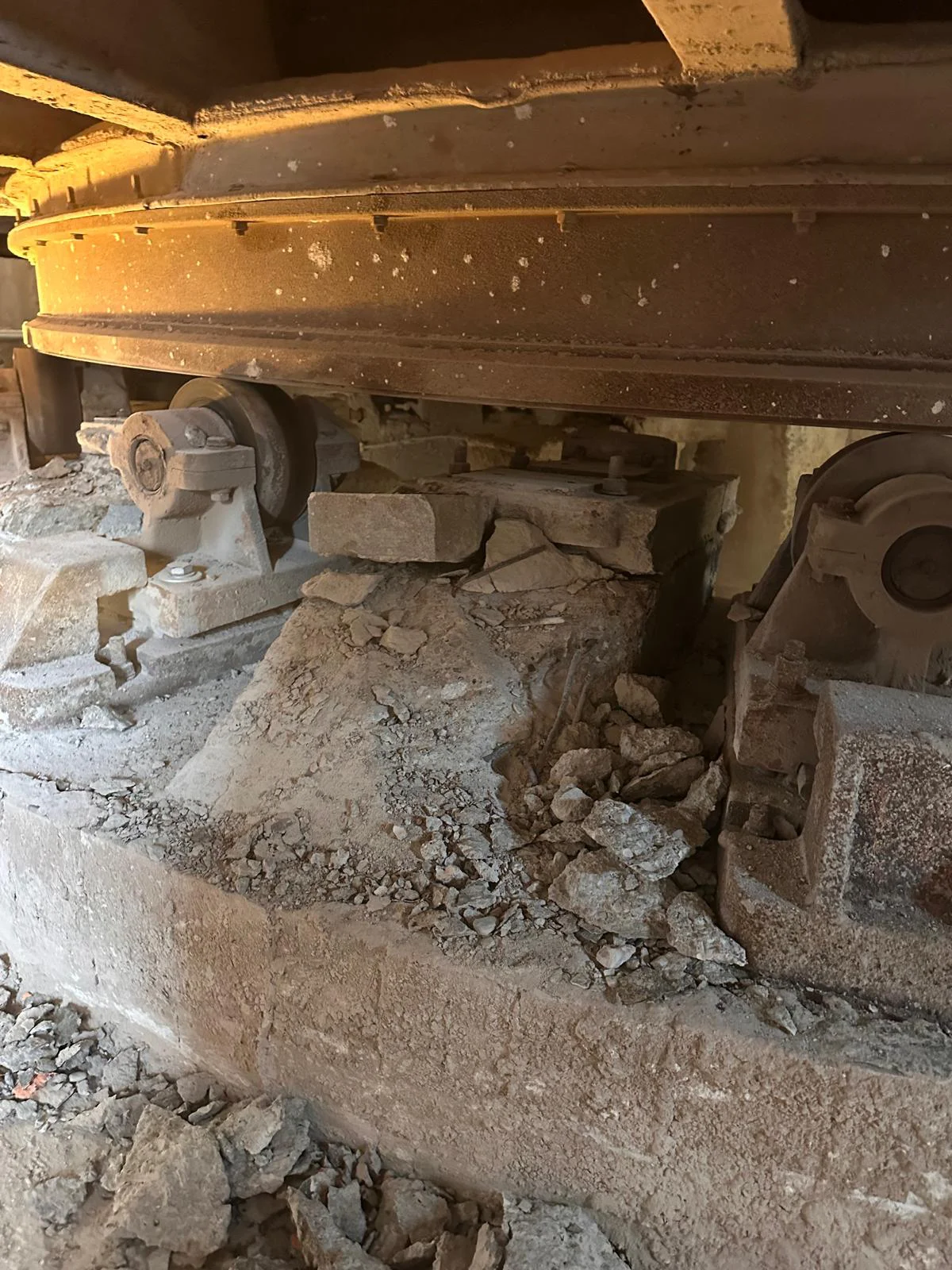 Odłupany, duży fragment zdegradowanego betonu z widocznymi elementami zbrojeniowymi.